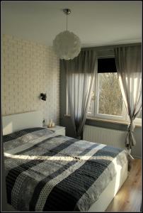 a bedroom with a black and white bed and two windows at Apartament Mieszko Kołobrzeg in Kołobrzeg