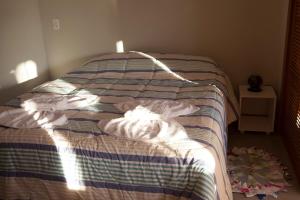 an unmade bed in a bedroom with the sun shining on it at Casas em Ilhabela, Linda vista, praia Itaguaçu, Vila Paulino, Colibri, Tuim e Tucano in Ilhabela
