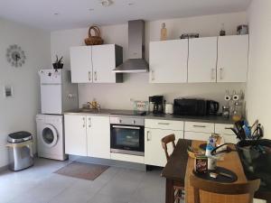 a kitchen with white cabinets and a table and a stove at Clos des lys in Vittel