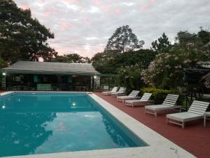 a swimming pool with lounge chairs next to a building at Cabañas Los Troncos in Ituzaingó