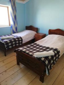 Habitación con 2 camas, paredes azules y suelo de madera. en Ushguli Hotel Riho en Ushguli