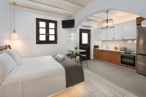 a bedroom with a large white bed and a kitchen at Lindos Shore Junior Suite in Líndos