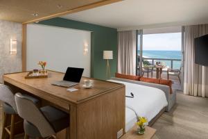 Un dormitorio con una cama y un escritorio con una computadora portátil. en Eden Roc Miami Beach, en Miami Beach