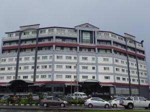 un grand bâtiment blanc avec des voitures garées devant lui dans l'établissement Penview Hotel, à Kuching