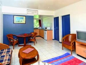 een woonkamer met een tafel en stoelen en een televisie bij Capricorn International Hotel in Nadi