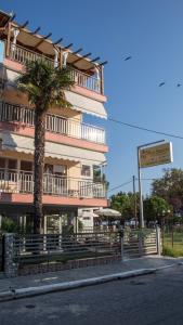 a building with a palm tree next to a street at Four Seasons 2 in Paralia Katerinis