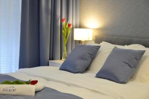 a bed with blue pillows and a vase with flowers on it at JessApart – Ochota Apartments in Warsaw