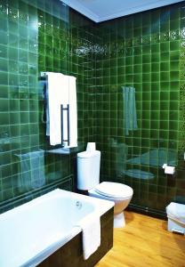 uma casa de banho com azulejos verdes, um WC e um lavatório. em Hospedium Hotel La Marina Costa da Morte em Cee