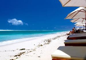 a beach with umbrellas and people sitting on the beach at Kubu Turah Homestay in Jimbaran