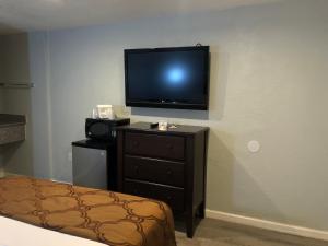 a room with a tv and a dresser with a bed at Relax Inn in Flagstaff