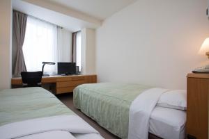 a hotel room with two beds and a desk at Hotel Sunroute Aomori in Aomori