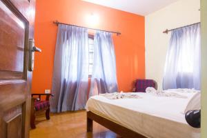 a bedroom with a bed with orange walls and a window at Villa Emmanuel 1BHk Holiday Homes in Candolim