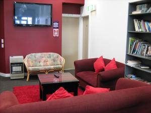a living room with two couches and a tv at Downtown Backpackers & Accommodation in Nelson