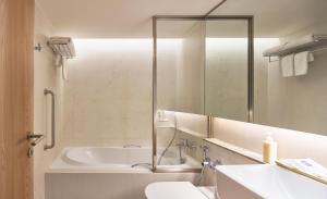 a bathroom with a tub and a sink and a mirror at Kritthai Residence in Bangkok