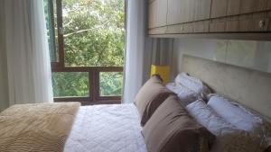 Loft luxo em Pedra Azul في بيدرا أزول: غرفة نوم بسرير ومخدات ونافذة