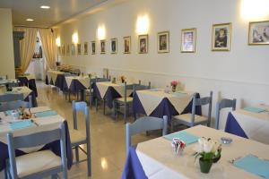 a dining room with white tables and blue chairs at Hotel Il Gatto in Rapallo