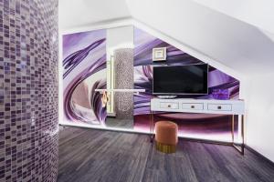 a living room with a tv and a wall mural at RQ Boutique & Unique Hotel in Győr