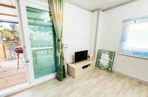 sala de estar con TV y ventana grande en Tobang Red Clay Pension, en Pohang