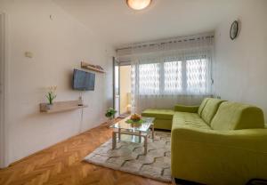 ein Wohnzimmer mit einem grünen Sofa und einem Tisch in der Unterkunft Apartman Andjela in Tivat