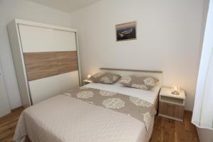 een slaapkamer met een wit bed met 2 kussens bij Apartments Krešan Soline in Sukošan