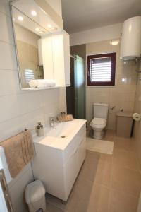 een badkamer met een wastafel, een toilet en een spiegel bij Apartments Krešan Soline in Sukošan