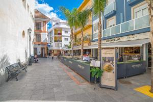 ulica ze sklepami, palmami i budynkami w obiekcie Apartment Calle Larga w mieście Fuengirola