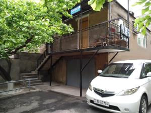 a white car parked in front of a building with a balcony at Hostel Sakharov & Tours in Yerevan