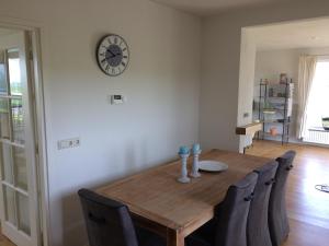 a dining room table with chairs and a clock on the wall at Wide ie Grou in Nes