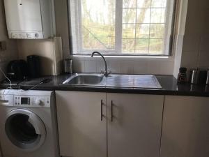 a kitchen with a sink and a washing machine at Waltham Abbey Private Property in Waltham Abbey