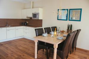 a dining room table with black chairs and a kitchen at Residence Aan de Kust in Noordwijk aan Zee