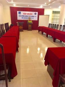 a conference room with red tables and chairs and a screen at Nhà Khách T284 in Buon Ma Thuot