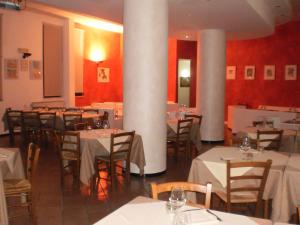a dining room with white tables and chairs and columns at RTA Le Corti in Grosseto