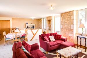 uma sala de estar com dois sofás vermelhos e uma cozinha em Charente Chambres d'Hôtes - B&B em Bernac