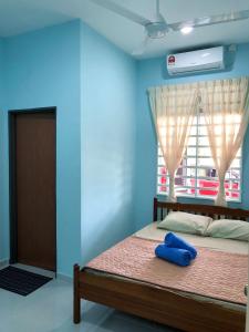 a bedroom with a bed with a blue wall and a window at Twin Homestay A in Kuala Terengganu
