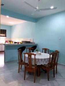a dining room with a table and chairs and a kitchen at Twin Homestay A in Kuala Terengganu
