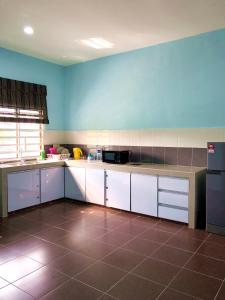 a kitchen with white cabinets and a blue wall at Twin Homestay A in Kuala Terengganu