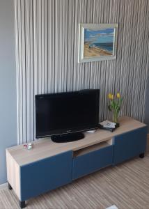 telewizor z płaskim ekranem siedzący na niebieskiej szafce w obiekcie Kawalerka Gdynia w mieście Gdynia