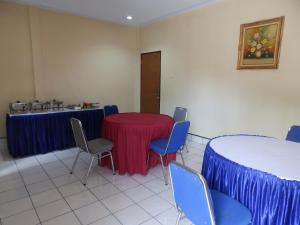 une chambre avec une table, des chaises et une table à jupes bleues dans l'établissement Bahari Family Hotel, à Bitung