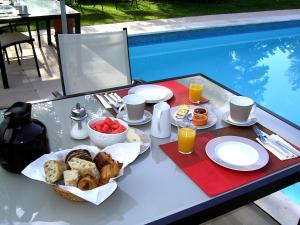 una mesa de desayuno con comida y bebida en una mesa junto a la piscina en Mas la Provence, en LʼIsle-sur-la-Sorgue