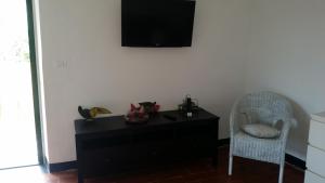 a black dresser with a chair and a television on a wall at Sol y Ombra in Voze