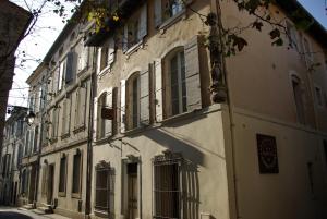 a white building with windows on a street at Hôtel Amphithéâtre in Arles