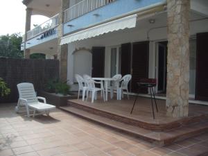 un patio con sillas blancas y una mesa en una casa en Apartament Neàpolis 2, en Sant Martí d’Empúries