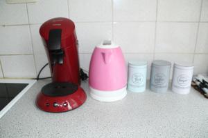 a red coffee maker and three cups on a counter at Appartement Ledeberg in Ghent