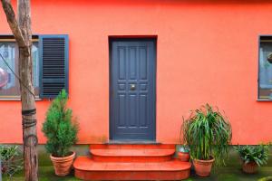 una casa naranja con una puerta azul y algunas plantas en La Maison de Titty & Margherita, en Piano di Sorrento