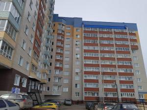 a large apartment building with cars parked in front of it at Апартаменты in Kirov