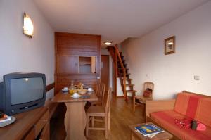 a living room with a tv and a table with a couch at Résidence Odalys Les Hauts du Rogoney in Val dʼIsère