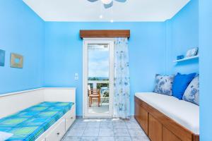 a blue bedroom with a bed and a balcony at Gerakini Sunshine Holiday Homes in Yerakiní