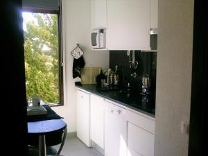a kitchen with white cabinets and a black counter top at Apartment Troia Garden in Troia