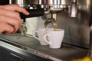 a person is pouring coffee into two coffee cups at Hotel Angelino in Ischia