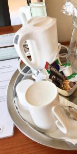 una bandeja con tazas blancas y platillos en una mesa en Beresford Road London Rooms, en Londres